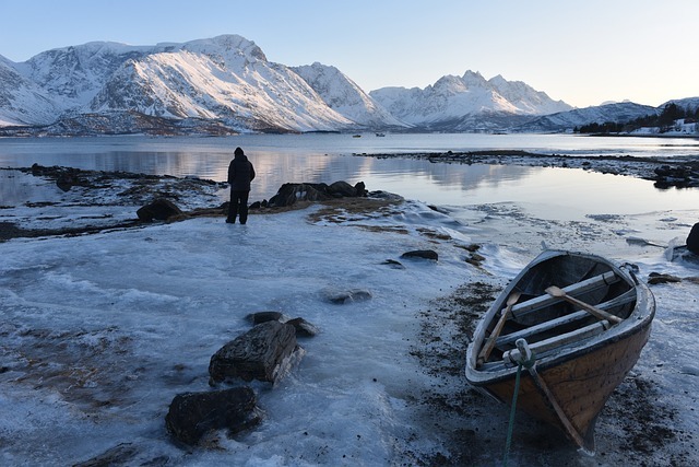 Image of a person and a boat on snowy icy estuary