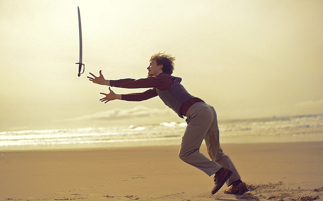 Image of a man juggling one sword on the beach