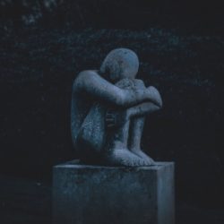 Image of a statue of a man huddling in guilt