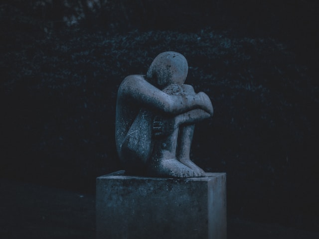 Image of a statue of a man huddling in guilt